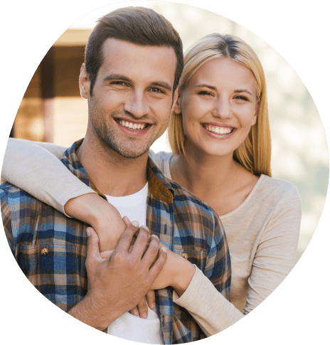 Smiling young man and woman holding each other outdoors