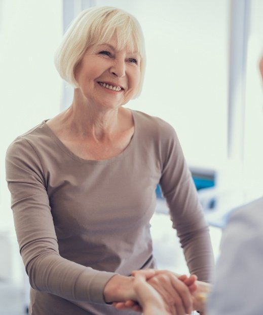 Smiling senior woman shaking hands with sleep specialist after sleep treatment in Frisco