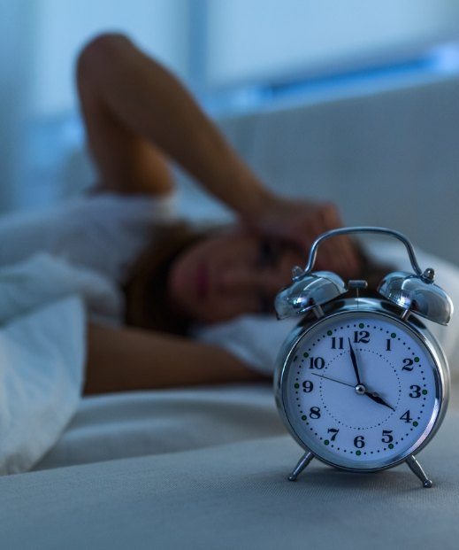 Woman lying awake in bed needing insomnia treatment in Frisco