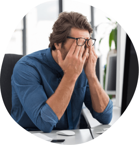 Man rubbing his eyes while sitting at desk