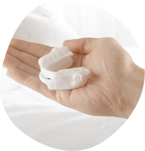 Person holding a white oral appliance in their hand
