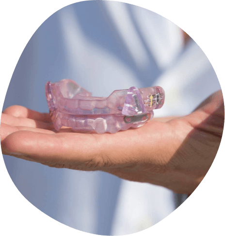 Person holding light purple oral appliance in their hand