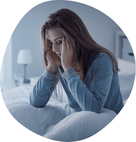 Woman sitting up in bed and touching her temples