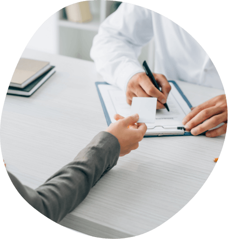 Patient handing a payment card across a desk to a doctor
