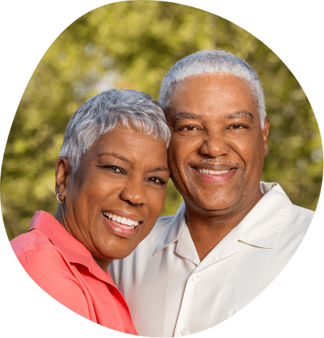 Senior man and woman smiling together with trees in background