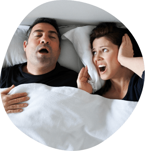 Woman in bed covering her ears next to snoring man