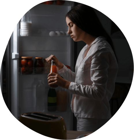 Woman taking juice bottle out of fridge at night