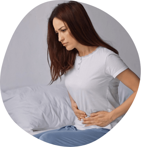 Young woman holding her stomach while sitting up in bed