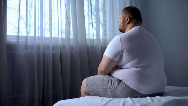 Obese man sitting on a bed